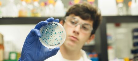 student holding a KnockOut lab plate